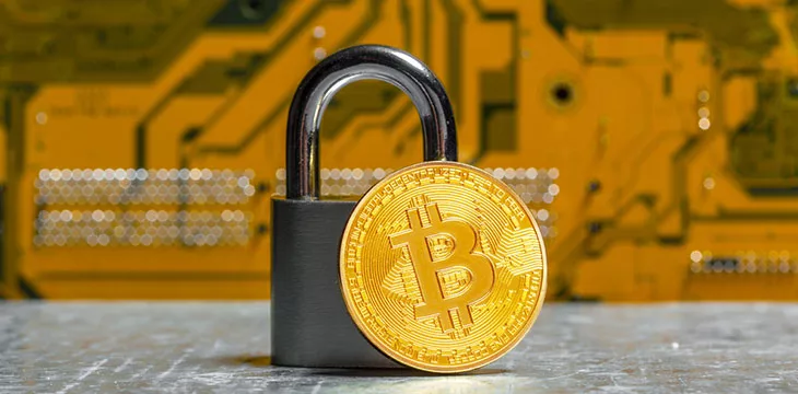 Gold bitcoin and padlock on motherboard background