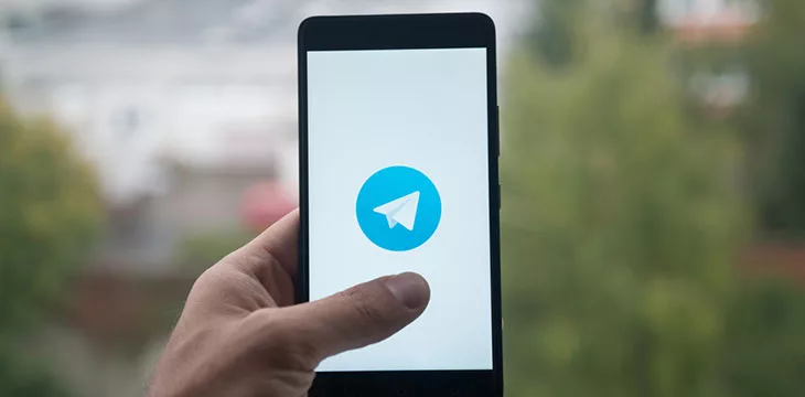 Man holding smartphone with Telegram logo with the finger on the screen