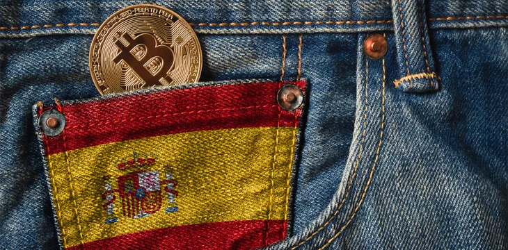 Cryptocurrency in the pocket of jeans with the flag of Spain on Jeans Denim Texture