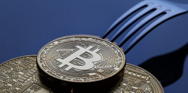 A fork with gold bitcoins on a blue background