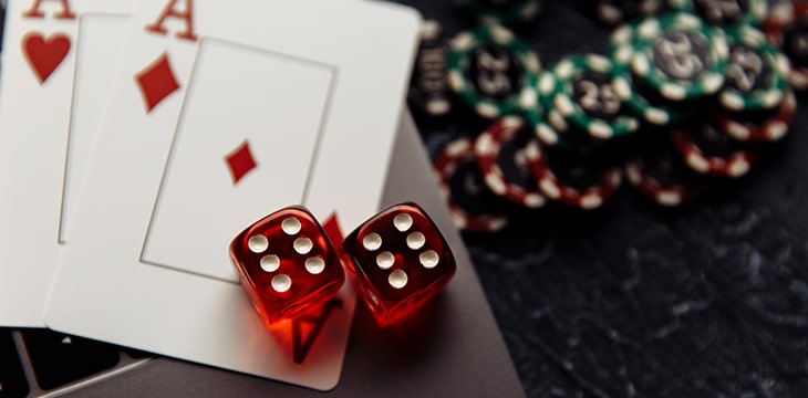 Poker chips, dice and playing cards on top of a laptop