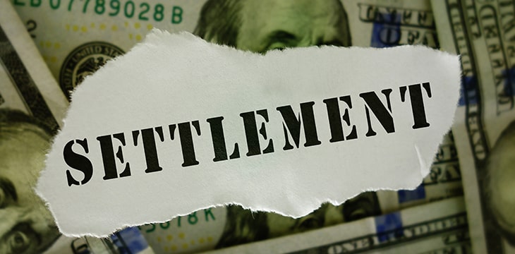 Settlement text on torn paper scrap over hundred dollar bills