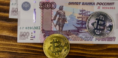 Golden and silver bitcoins and five hundred russian rubles bills on wooden background