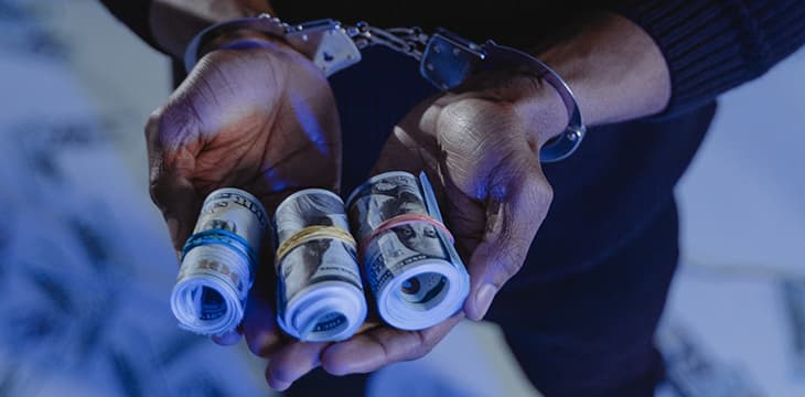 A man on handcuffs holding money