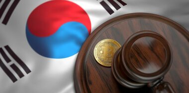 Bitcoin and judge gavel laying on flag of South Korea.