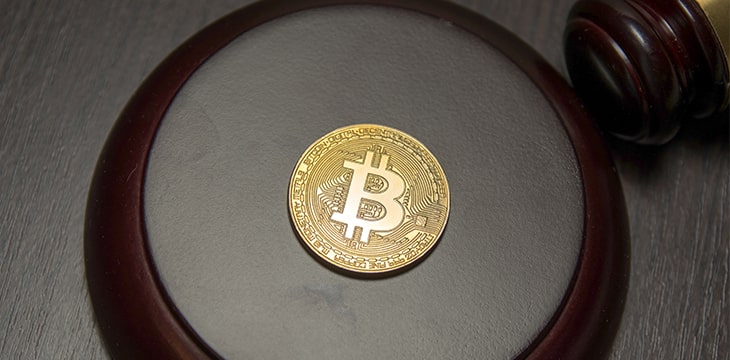 Golden bitcoin on wooden pedestal of judge gavel