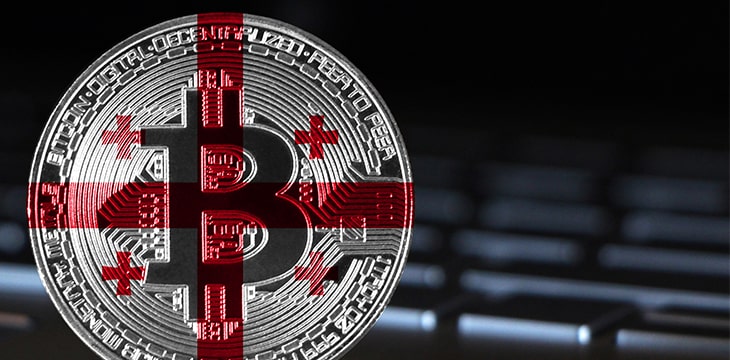Bitcoin close-up on keyboard background, the flag of Georgia is shown on bitcoin.