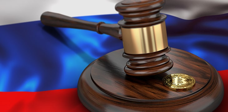 Bitcoin and judge gavel laying on flag of Russia.