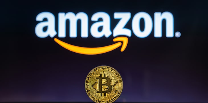 Amazon logo on a computer screen with a stack of Bitcoin cryptocurency coins