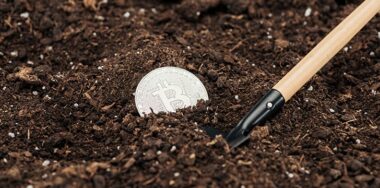 Selective focus of toy shovel near bitcoin in ground, protecting nature concept