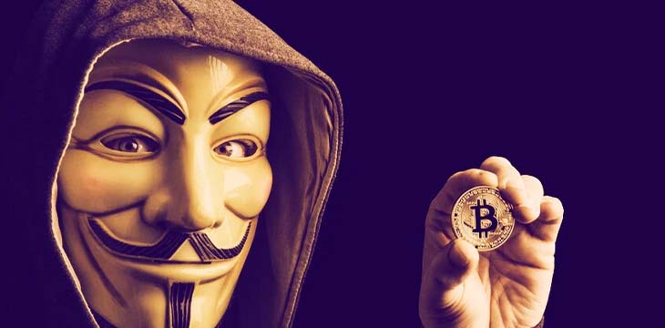 a masked person holding a bitcoin