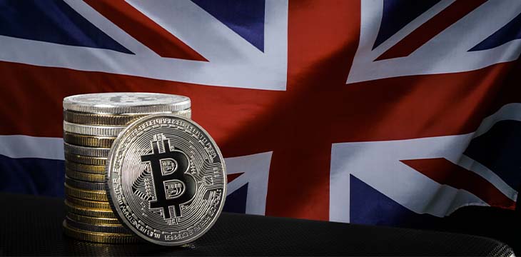a stack of coins with a bitcoin logo on it and a flag of the UK behind it