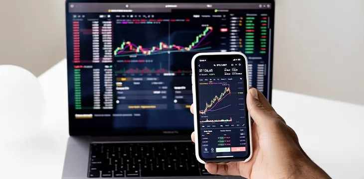 person infront of computer holding smartphone