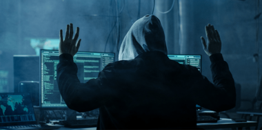 A man wearing a hood in front of computer