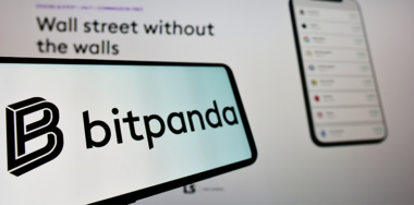 Mobile phone with logo of Austrian crypto exchange company Bitpanda GmbH on screen in front of business website. Focus on left of phone display