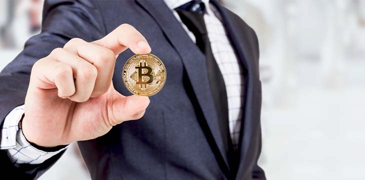 Man in suit holding a bitcoin coin