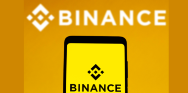 the Binance logo is displayed on a smartphone screen and in the background