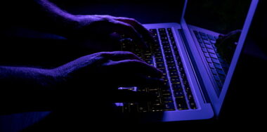 Man typing on laptop computer keyboard at night