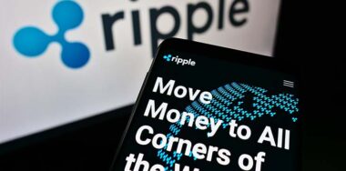 Mobile phone with webpage of American technology company Ripple Labs Inc. on screen in front of logo. Focus on top-left of phone displa