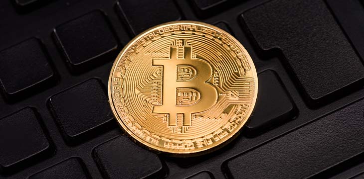 Close up view of golden bitcoin in black keyboard