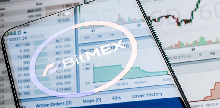 A smartphone with the BitMEX logo on the background of the live trading webpage.