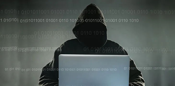 A hacker with a hood with laptop