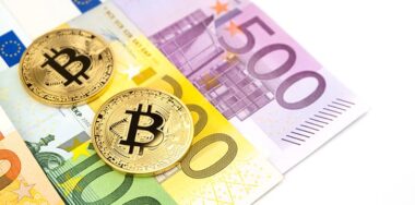 Golden bitcoin on pile of various euro banknote background.