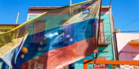 Venezuelan Flag with colorful house as background