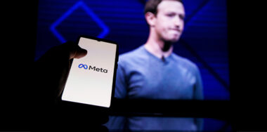Meta logo on screen and Mark Zuckerberg on background
