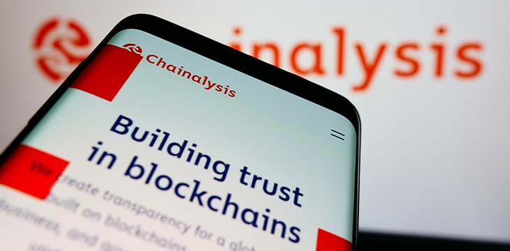 Mobile phone with website of cryptocurrency company Chainalysis Inc. on screen in front of logo. Focus on top-left of phone display.