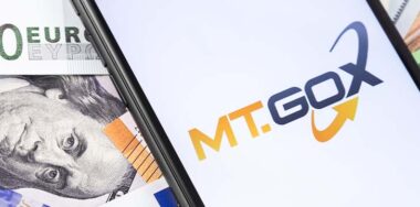 Money and MT.GOX logo of exchange on the screen smartphone. MT.GOX is popular largest cryptocurrency exchange on the market.