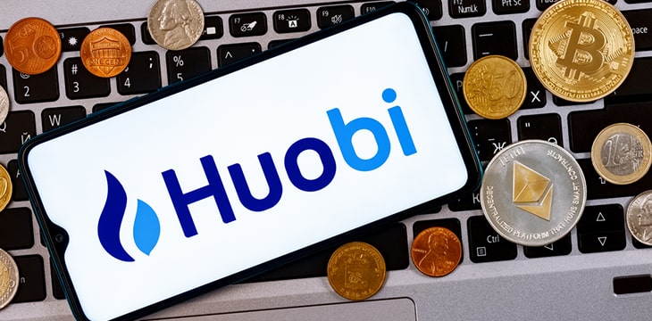 phone with huobi logo on laptop keyboard with coins