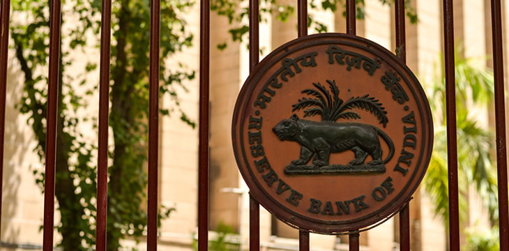 RBI logo on the closed iron gate of Reserve Bank of India (RBI) building at Patel Chowk, Connaught Place with the office building in the background in Delhi, India