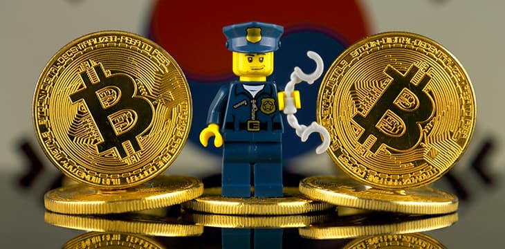 Physical version of Bitcoin, Police Officer (as Lego figure) and South Korea Flag.