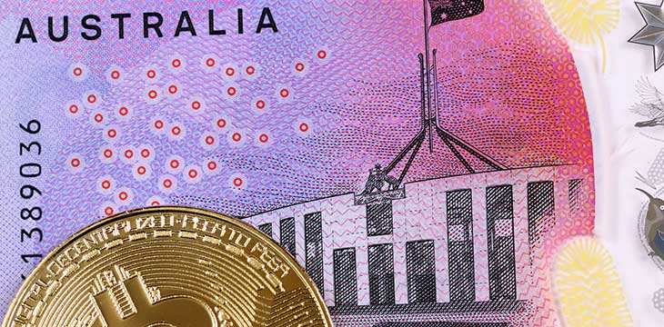 A close up image of a golden bitcoin with an Australian five dollar bill