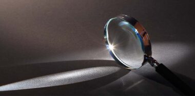 Closeup of magnifying glass standing on dark surface with beam of light — Photo