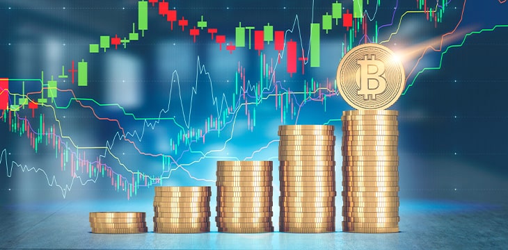 Stacks of bitcoins standing against a blurred office background with multicolored graphs in the air