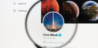 Elon Musk Official twitter web page on screen through magnifying glass