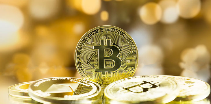 bitcoin on stack of gold coins