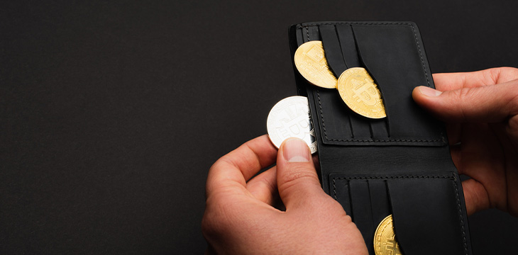 Cropped view of man holding wallet with different bitcoins isolated on black