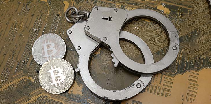 Two coins of bitcoin and handcuffs lie on the background of an electronic printed circuit board. The concept of a violation of the law, cybercrime, financial fraud. — Stock Editorial Photography