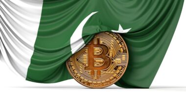 Pakistan flag draped over a bitcoin cryptocurrency