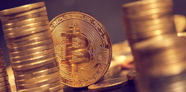 Golden bitcoin among stacks of coins