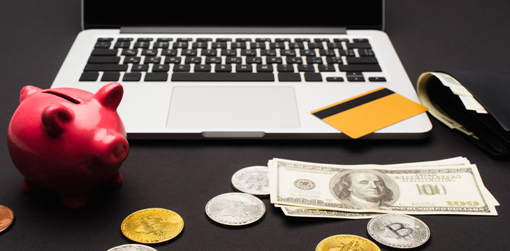 Bitcoins near dollars and laptop on black background