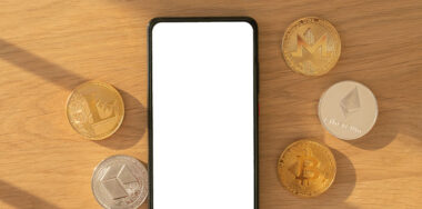 Cryptocurrency coins and smartphone on table