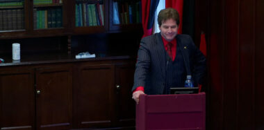 Dr. Craig Wright on a stage with a podium as a speaker