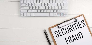 Home office workspace with keyboard, clipboard and pen with text SECURITIES FRAUD on a white wooden background , business concept — Photo