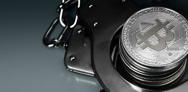 Bitcoins and handcuffs over blue background
