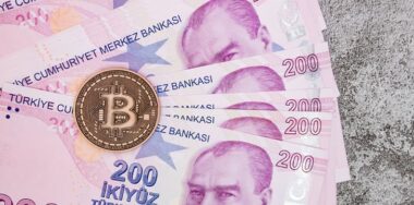 Turkish lira banknotes and bitcoin coin on background.