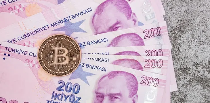 Turkish lira banknotes and bitcoin coin on background.